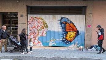 publico junto a un mural de la Galería Urbana en proceso